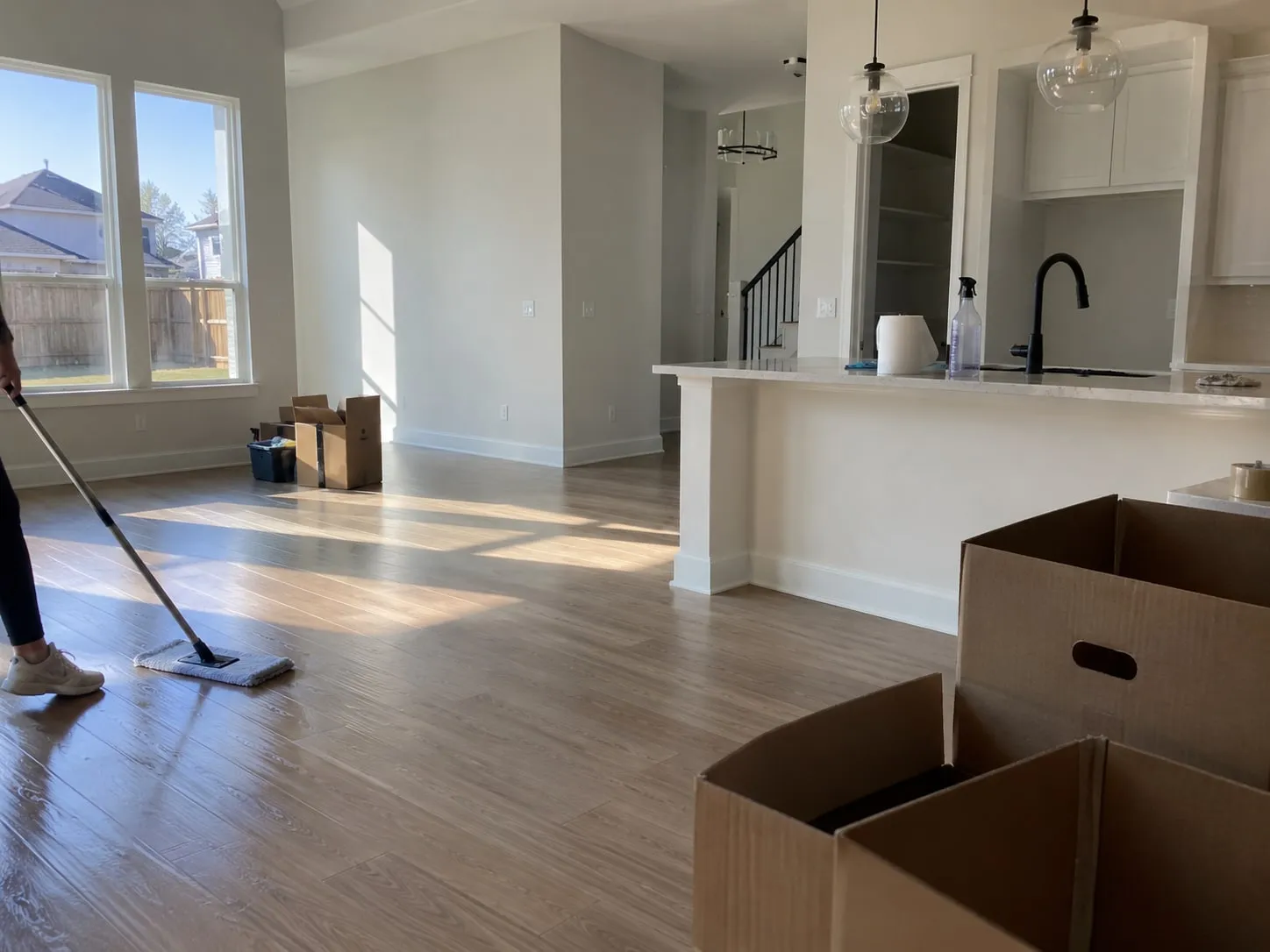 Cleaner mopping hardwood floors in an empty home during a move-out cleaning in Frisco, TX